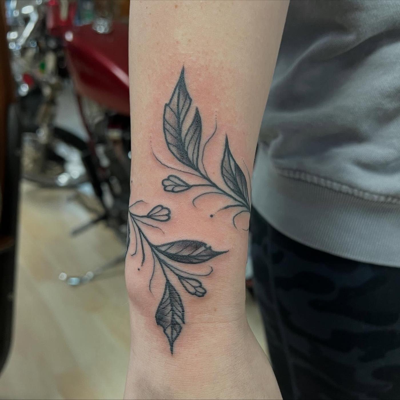 A fine line botanical tattoo on an arm